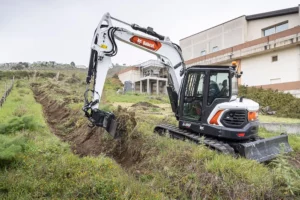 Bobcat mini excavator digging hole in ground - available for rental