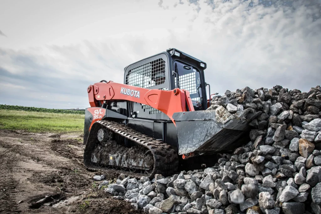 Track loader holding several large rocks - available for rent